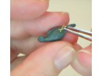 Inserting a foot into the body of the polymer clay miniature parrot