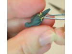 Inserting the second foot into the body of the polymer clay miniature parrot